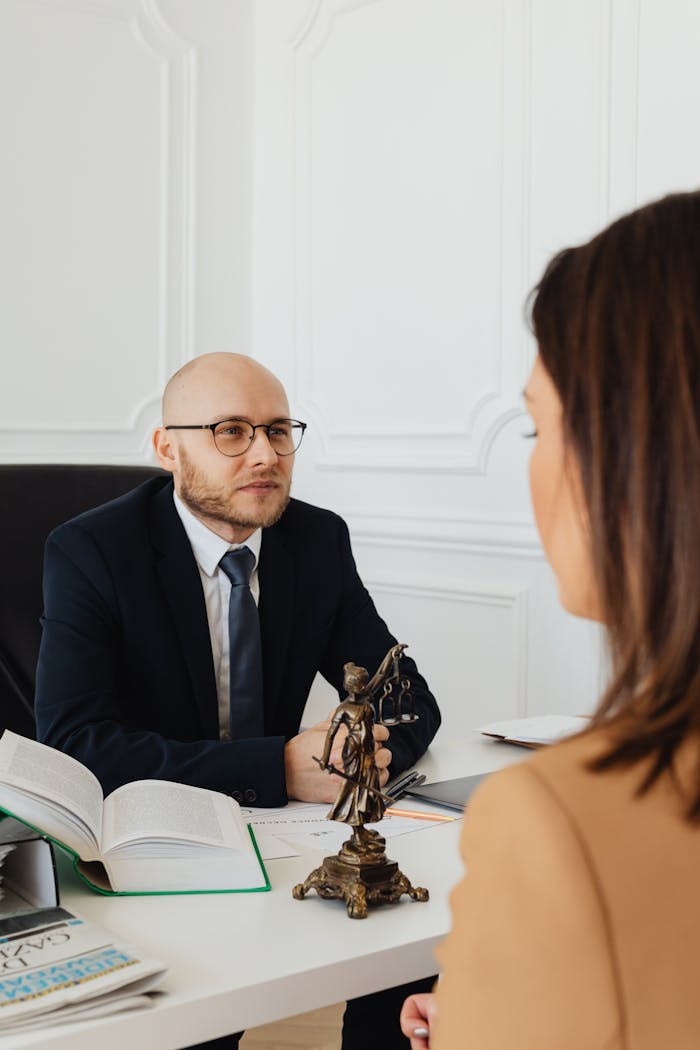 A lawyer consulting with a client in a modern office featuring Lady Justice.
